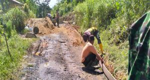 Warga dan Anggota Satgas TMMD Reg Ke-120 Pasang Papan Mal Jalan Rabat Beton